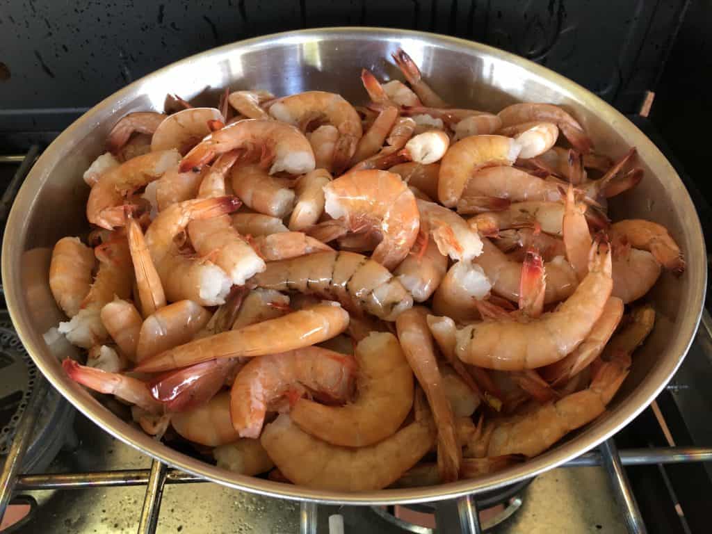Raw shrimp in a large stainless steel bowl.