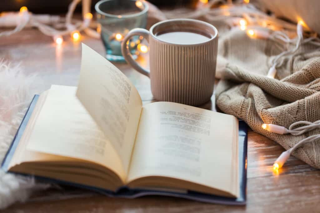 What is hygge? hygge and cozy home concept - book and cup of coffee or hot chocolate on table